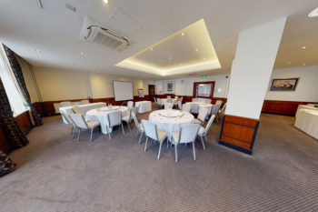 Meeting table at Mercure London Watford, black leather office chairs around a wooden table with glasses of water and apples