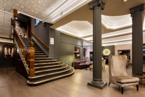 High backed velvet armchair in the lounge at Mercure Leicester The Grand Hotel, dramatic grey pillars and large staircase
