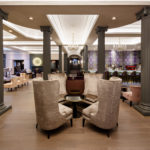High backed velvet armchairs in the lounge at Mercure Leicester The Grand Hotel, dramatic grey pillars and chandeliers