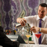 Bar man serving cocktails to a customer at the bar