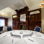 Mercure-branded pens and paper arranged for a meeting in the Cromwell meeting room, grand wooden fireplace in the background