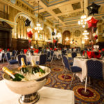 Wide view of The King's Hall dressed for an event, with white tablecloths and black, white and red balloons, Mercier Champagne in the foreground
