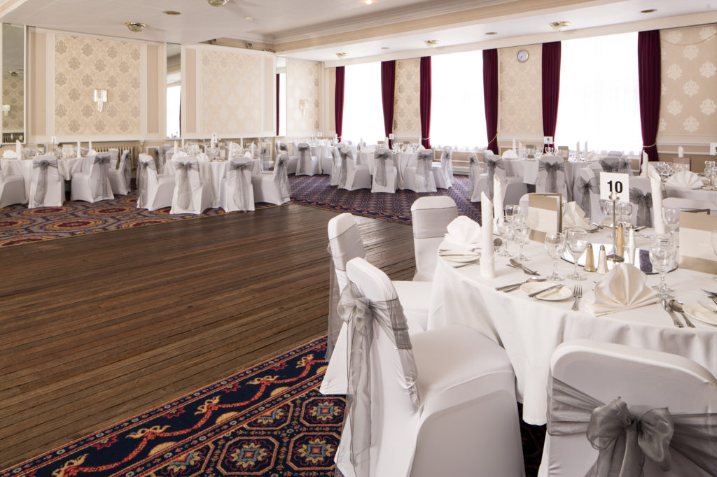 Wedding breakfast set up in the Queen's Ballroom at Mercure Leicester The Grand Hotel, white and silver theme and a dark wooden dancefloor