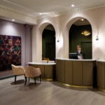 Busy receptionists behind marble reception desk, geometric artwork on the wall