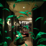 Green origami artwork hanging in the hotel window, with reception visible behind